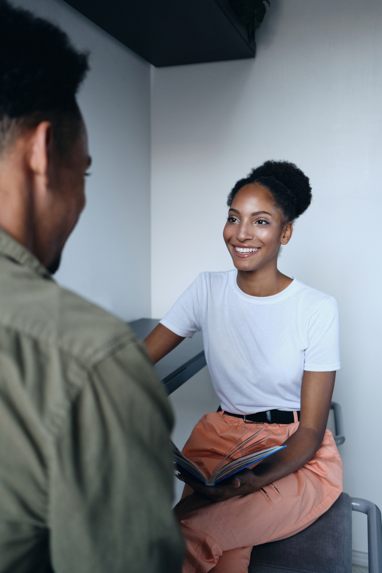 Young pretty casual African American woman happily talking with co worker in modern office